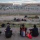 Imigrantes se recuperam às margens do Rio Grande, na divisa entre Estados Unidos e México, em Ciudad Juarez (Justin Hamel/Bloomberg)