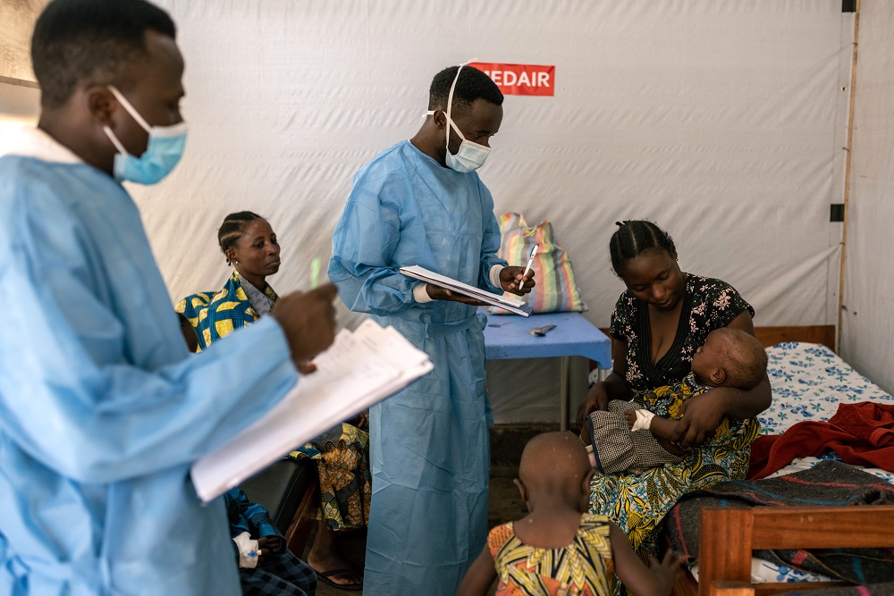 Profissionais de saúde com crianças recebendo tratamento para mpox em uma sala de terapia no centro de tratamento de mpox de Munigi, em Kivu do Norte, República Democrática do Congo, em 17 de agosto (Arlette Bashizi/Bloomberg)