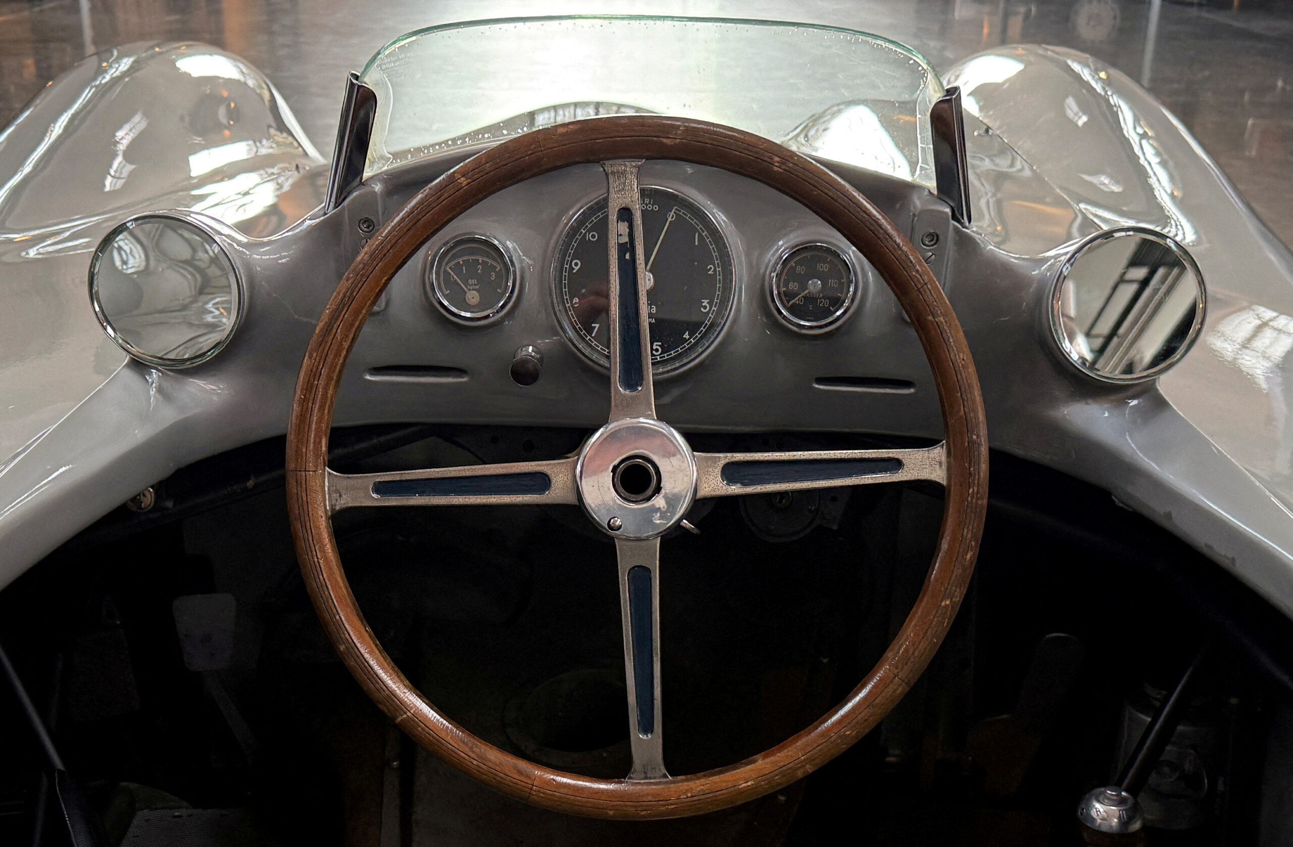 Foto do carro Mercedes aerodinâmico com os pilotos Stirling Moss e Juan Manuel Fangio durante uma corrida.