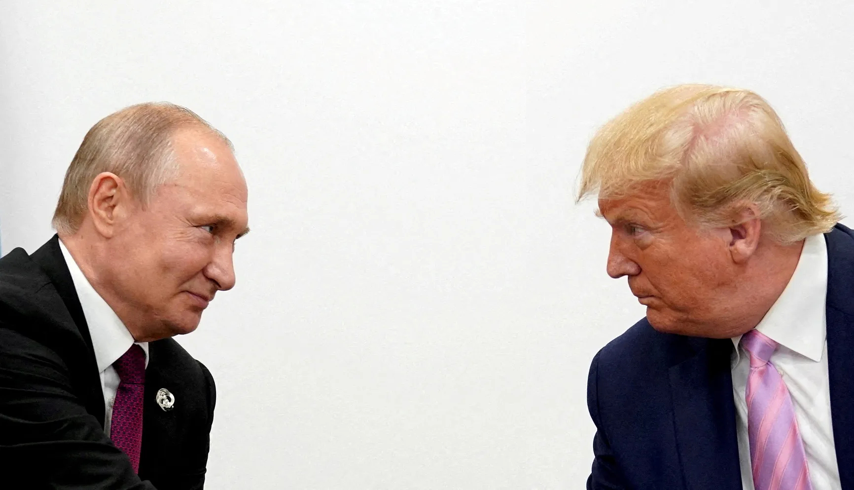 Donald Trump e Vladimir Putin se cumprimentando durante a conferência.