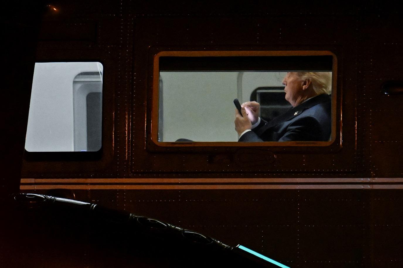 O líder americano, Donald Trump, utiliza seu celular no Marine One no Aeroporto Executivo de Leesburg.