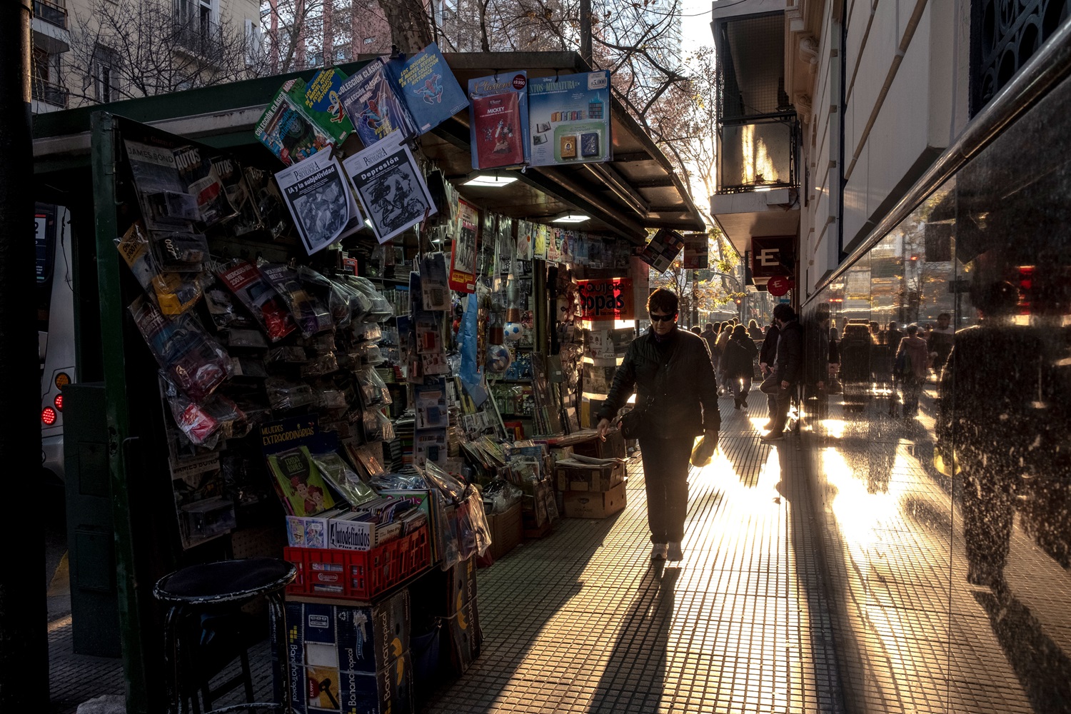 Pessoas passando por banca de jornal em Buenos Aires.
